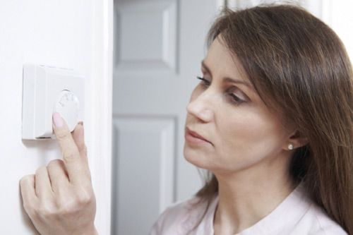 Homeowner adjusting their heating thermostat